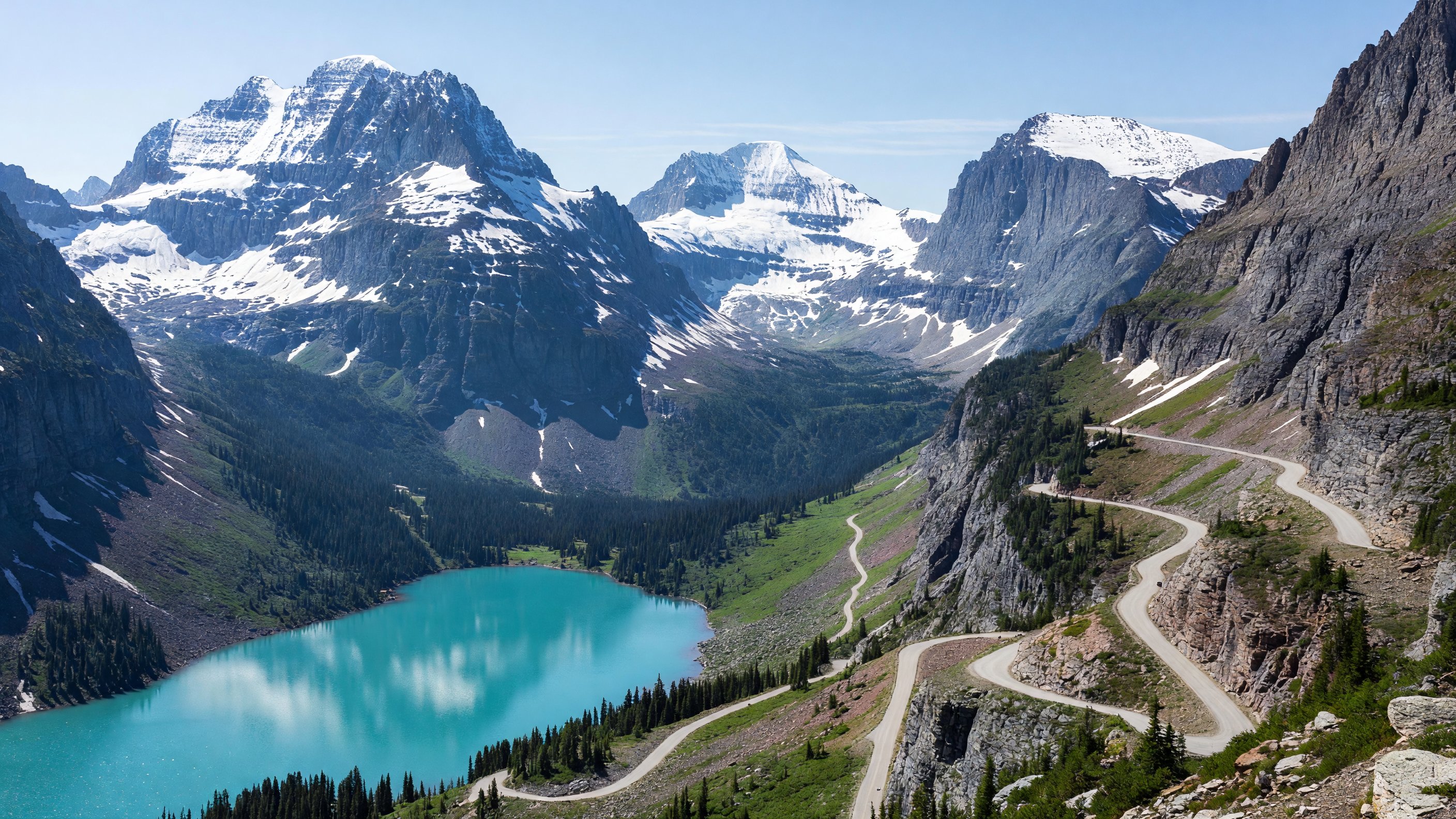 Going-to-the-Sun Road winding through Glacier National Park's alpine terrain with snow-capped peaks and turquoise lake below