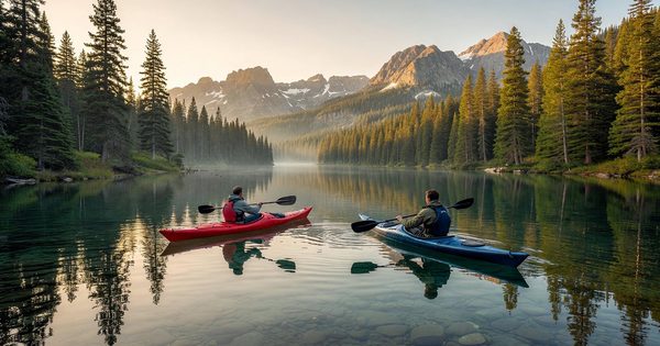 A couple paddling a bright red canoe across a calm wilderness lake surrounded by boreal forest, early morning light on still water